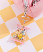 Keyring attached to a backpack zipper. The clear pouch features Pusheen graphics and has the phrase "best by: BA/NA/NA" in white text across the bottom.