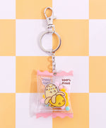 Pusheen Fruits Keyring in its packaging. The keyring is attached to a cardboard backer card that features a yellow and white checkered print and a blue hanger.