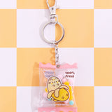 The Pusheen Fruits Keyring lies on a yellow and white checkered background. The clear pouch is attached to a silver chain, circle keyring to add keys to, and a lobster claw clasp.