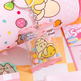 Banana Keychain in front of various Pusheen Fruits products including a pink graphic water bottle, notebook, and stationery set.