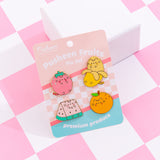 Front view of the Pusheen Fruits Pin Set. The set includes four pins of Pusheen as fruits including a pink strawberry, yellow banana, pink and green watermelon slice, and an orange.
