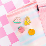 Fruits Pins attached to a bag. The multi-colored pins have gold lines outlining the Fruit features and Pusheen's facial features.