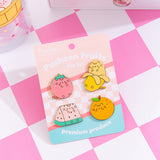 Pusheen Fruits Pin Set and backer card. The backer card has a pink checkered print, solid pink and blue backgrounds, and features the phrase "premium produce" at the bottom in white.