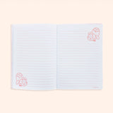 Interior view of pink banana notebook. On the white pages are light pink writing lines and pink graphics of Pusheen as a banana in both the bottom left corner and top right corner of the opened pages.