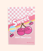 Front view of the notebook in the Pusheen Fruits Stationery Set. The pink notebook has a graphic of Pusheen as two pink cherries on stems. Phrases included on the front of the notebook include “sweet,” “fresh!,” “open,” and “100% real cute.” The background of the notebook has a pink checkered print with pink and yellow stripes.