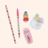 Close-up view of the contents of the Pusheen Fruits Stationery set. The pencil, pen, sticky notes, eraser, and highlighter include graphics and prints of Pusheen the Cat as various Fruit characters including a pineapple, cherries, kiwi, pear, blueberry, pear, banana, strawberry, orange, and apple.