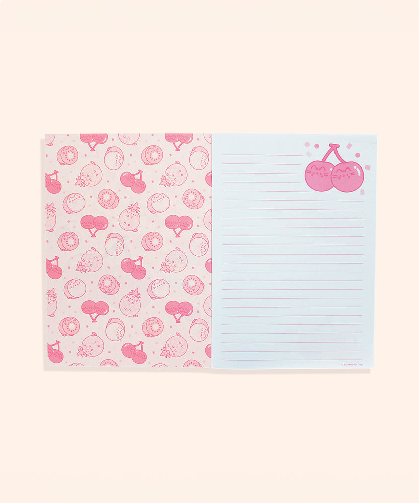 Interior view of stationery notebook. The protective first page is shades of pink and features a pattern of Pusheen as various fruits including pineapple, kiwi, cherry, and lemon. The next pages show the white with pink-lined interior writing pages.