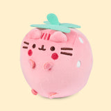 Left quarter view of the light pink-colored Pusheen Squisheen. In this angle, Pusheen’s triangle ears can be seen coming off the light pink round plush body. 