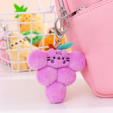 Close-up shot of Pusheen Fruits character: grapes. The purple cluster of grapes plush keychain is attached to a pink bag with the various other fruits character keychains shown in the background.  