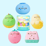 Fruits Surprise Squishy lie on a desk. The five fruits surrounded the packaging capsule that each squishy comes in. The five squishys each stand around 2" tall.