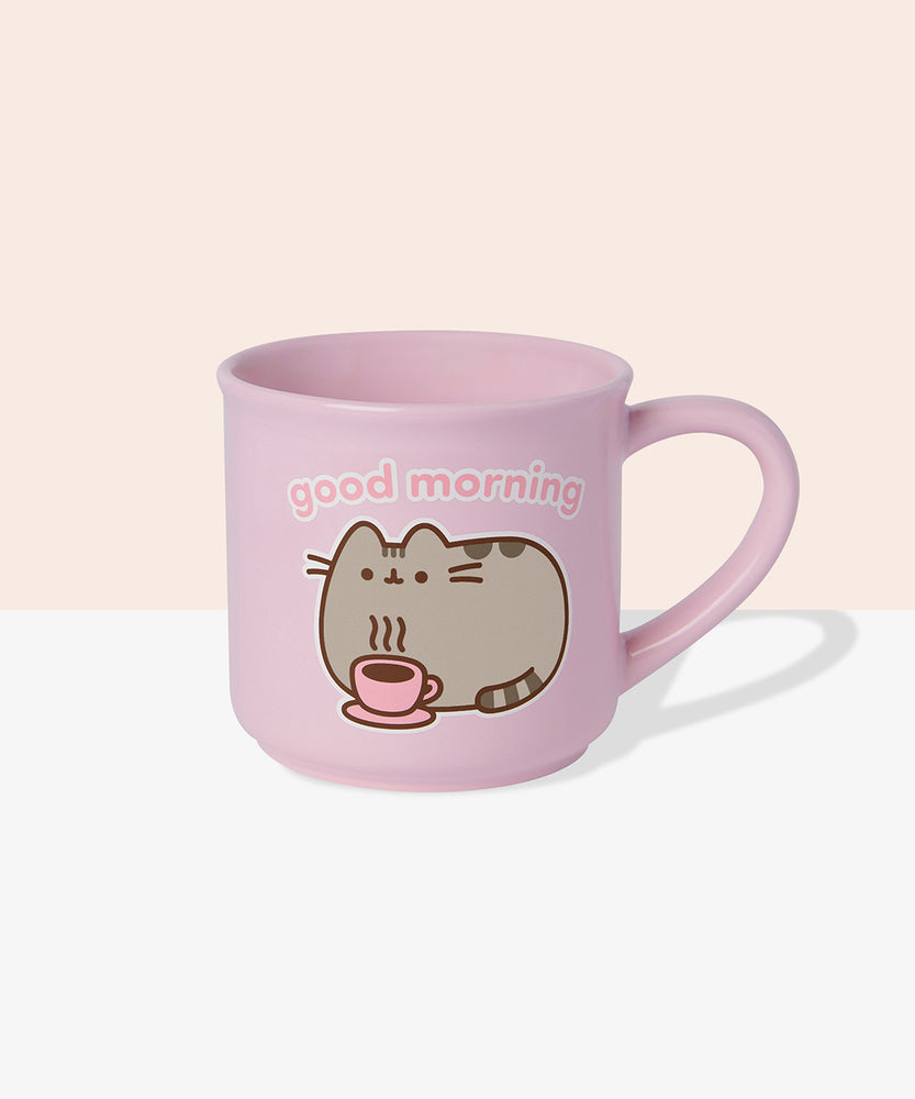 Back view of Pusheen pink mug. The light-pink cup features a grey and brown graphic of Pusheen relaxing with her own hot beverage in a pink mug. The graphic on the back matches the graphic on the front. 