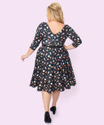 Model shows off the back of the Pusheen Halloween Dress. The flowy, stretching dress has the allover pattern continued on the back of the dress. The back has a V-shape neckline, the sleeves are three-quarter length, and the hem falls past the model’s calves. 