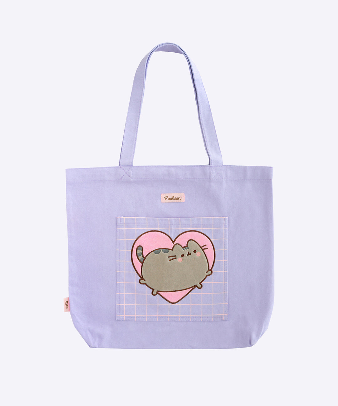 A tote bag is posed in front of a purple background. The purple tote has an appliquè of Pusheen the Cat blushing and jumping on the front pocket. The handles of the bag are purple, and the top has the Pusheen the Cat logo in pink and brown. 