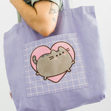 A model holds the Pusheen Heart Deluxe Tote Bag on shoulder to show the scale and size of the bag.  