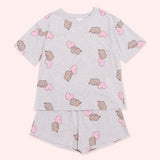 Hearts Pajama Set lies as a set on a background. The oversized grey t-shirt has Pusheen the Cat and mink hearts graphics on the top. The stretchy grey shorts have the same pattern as the Pusheen pajama top. 