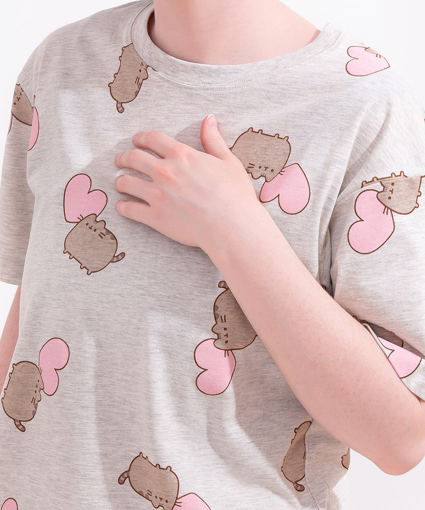 A close-up view of the gray pajama top. The top has an oversized fit and an all over print of Pusheen and a light pink heart. 