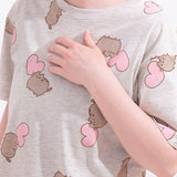 A close-up view of the gray pajama top. The top has an oversized fit and an all over print of Pusheen and a light pink heart. 
