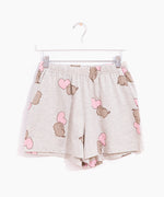 Hung on a white hanger, the Pusheen Pajama Shorts are hung out to show the full length of the shorts. The gray shorts are covered in a pattern of gray Pusheens and pink hearts. 