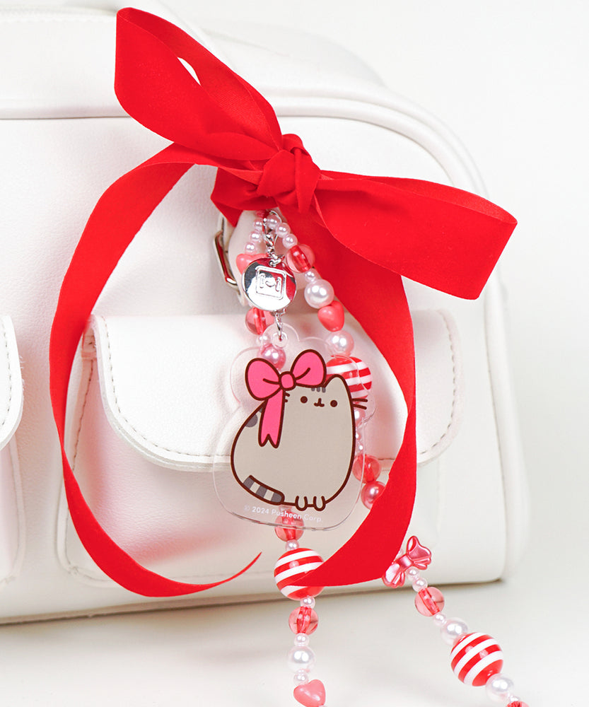 Holiday phone charm attached to a white bag. The wristlet has a mix of red and white beads alternating on the entire string.