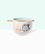 Front view of Pusheen Hot Ramen Bowl and Chopstick Set. The chopsticks rest in a notch on the lip of the white bowl. A graphic of Pusheen as a teal dragon, also known as Dragonsheen, is on both sides of the bowl. The dragon is lighting a fire with the phrase HOT printed above the multi-color fire.