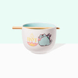 Front view of Pusheen Hot Ramen Bowl and Chopstick Set. The chopsticks rest in a notch on the lip of the white bowl. A graphic of Pusheen as a teal dragon, also known as Dragonsheen, is on both sides of the bowl. The dragon is lighting a fire with the phrase HOT printed above the multi-color fire.