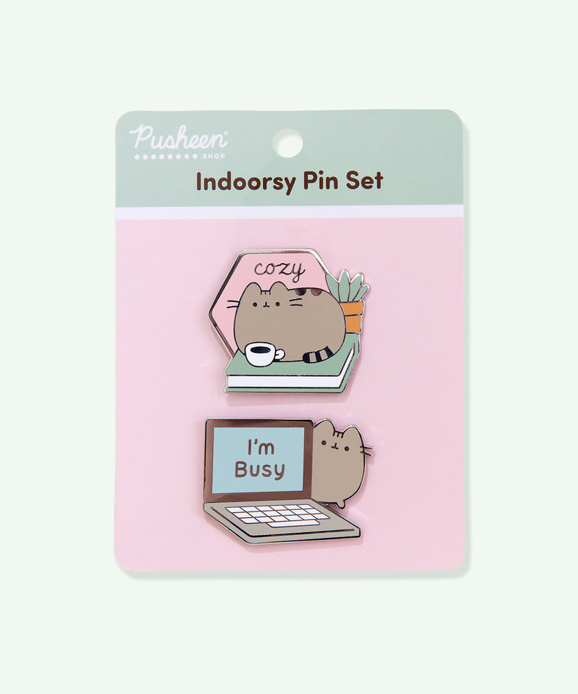 The pin set is attached to a cardboard backing featuring a two-tone pink and light green background. The pin set is standing in front of a light green background. 