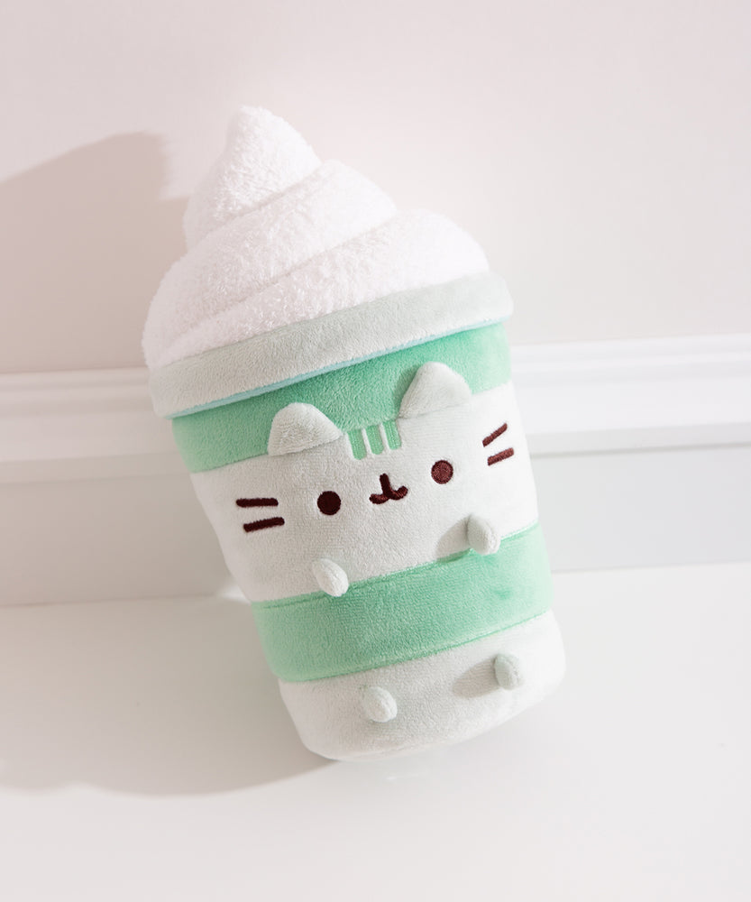 Pusheen Matcha Latte Plush lies on a plush pink blanket that highlights the soft green and white colors of the plush.