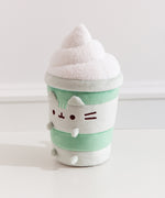 Left quarter view of the Matcha Latte Plush. The drink-inspired plush has a fuzzy whipped topping in a swirl pattern on top.