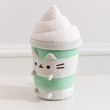 Left quarter view of the Matcha Latte Plush. The drink-inspired plush has a fuzzy whipped topping in a swirl pattern on top.