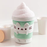 Matcha Latte-inspired Cat plush surrounded by desk items such as a candle and coffee cup.