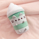 Pusheen Matcha Latte Plush lies on a plush pink blanket that highlights the soft green and white colors of the plush.