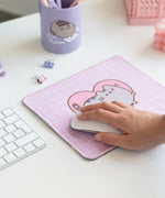 Model holds onto a computer mouse that sits on top of the Pusheen Mouse Pad.