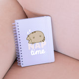 Front cover of the Pusheen Naptime Notebook. On the center of the light purple spiral notebook is a graphic of Pusheen the Cat sleeping on top of the phrase "nap time."