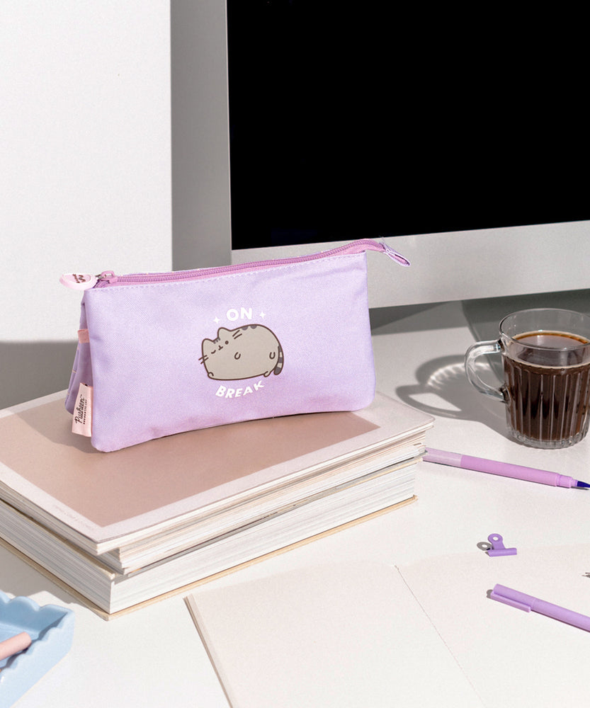 Pusheen On Break Accessory Case sits atop a desktop. The purple case has three compartments that are all accessible through the top zipper.