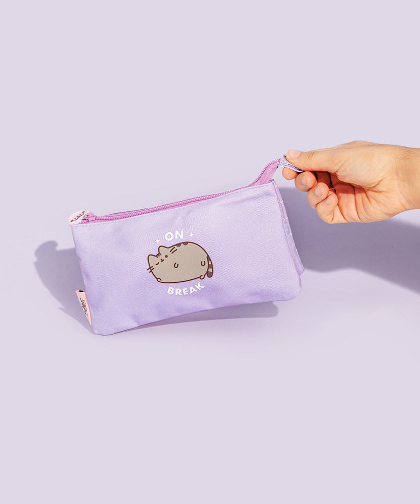 Model holds silicone pull tab on zipper of the Pusheen On Break Accessory Case. The purple case features a graphic of Pusheen the Cat winking on the front.