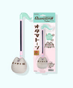 Pusheen Otamatone next to its packaging The mint green and pink packaging says "Otamatone," "Pusheen," and "FUN! Toy Musical Instrument."