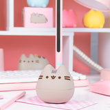 Front and partial side view of the Pusheen Otamatone. The grey, pink, and mint colored toy resembles the shape of a musical note.