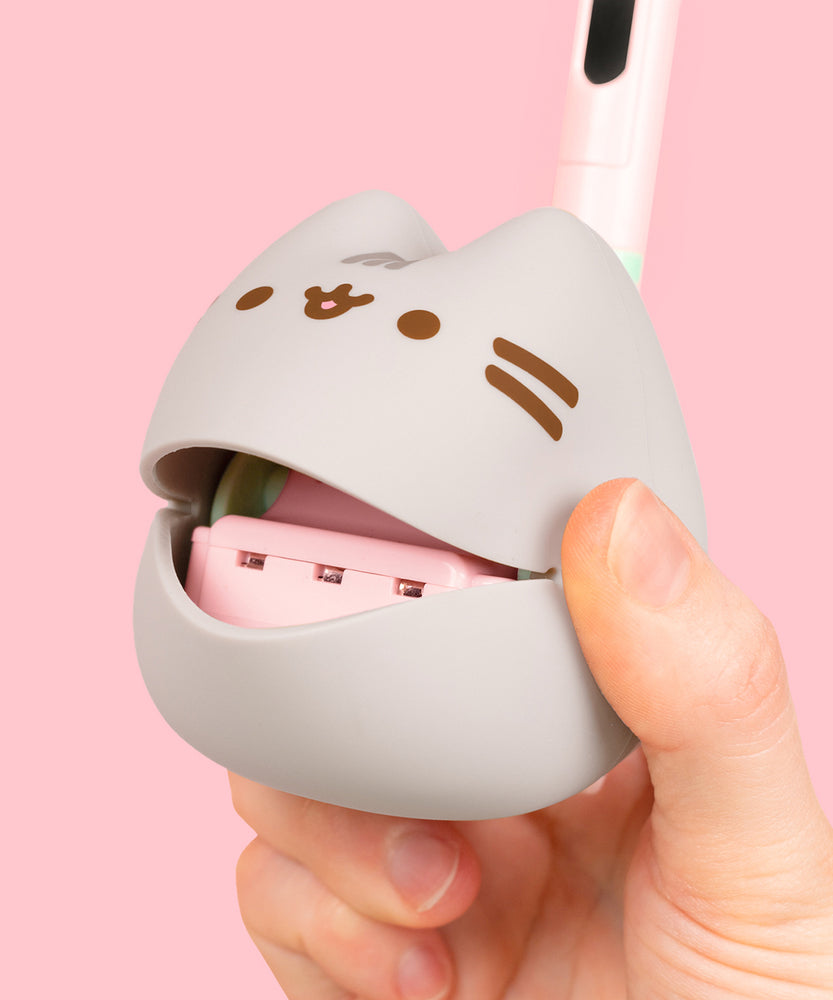 Close-up view of the musical mouth of the Pusheen Otamatone. The gray body has Pusheen's gray head stripes as well as her brown whiskers, eyes, and mouth printed in a dark brown color on the front.