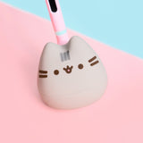 Front view of the Pusheen Otamatone. The toy has a pink and mint green stem that leads to a gray rounded plastic bottom that opens towards the bottom to make sounds.