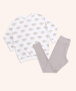 The Pusheen Patterned Loungewear Set lies on a yellow background. The set includes a cream-colored tunic top with an all over print of Pusheen the Cat in her classic grey and brown coloring. The set also includes taupe-colored legging bottoms that are folded in this image. 