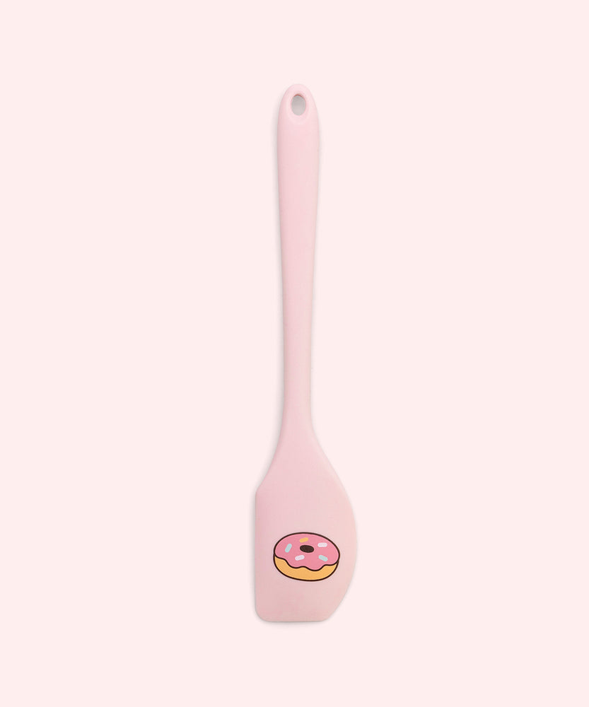 Close-up of included pink spatula in the set. At the scoop end of the spatula is a printed graphic of a pink glazed donut with multi-color sprinkles.