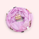 Collapsed view of the pet tunnel that has a plush dangle of a slice of strawberry cake on one end.