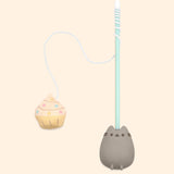Front view of Pusheen Pet Cupcake Teaser Toy. The toy has a long mint-green stick with a grey and brown molded Pusheen handle at the end. At the top of the stick is a long white string that has a cupcake plush toy at the end. The cupcake plush pet toy has light yellow frosting, multi-color sprinkles, and a yellow base. 
