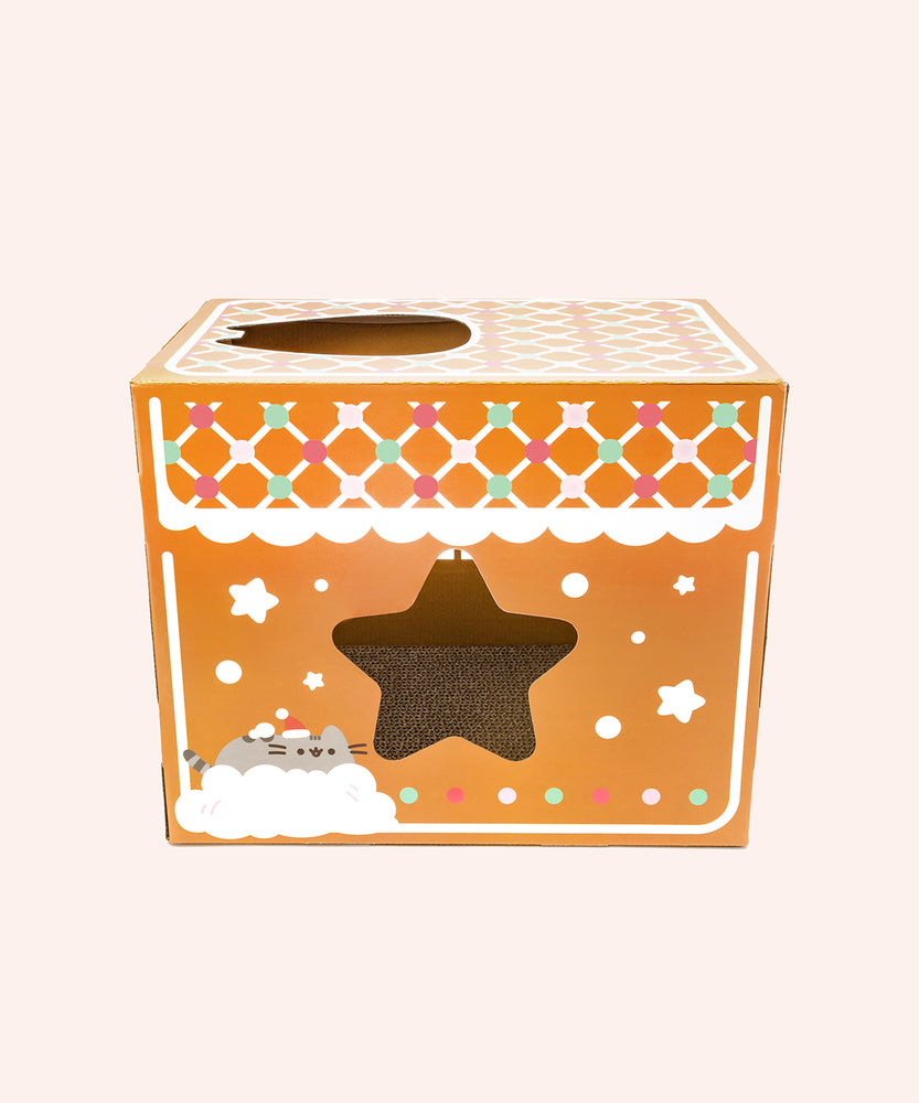 Alternate side view of the cat scratcher gingerbread house. This side of the box features a graphic of Pusheen the Cat in a pile of snow as well as a cut out in the shape of a star.