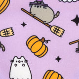 Close-up of the Halloween Pet Bandana pattern. The print shows Pusheen as a witch wearing a purple hat and riding a broom, Pusheen as a white ghost, and orange pumpkins and black stars on a purple background.