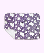 The Halloween Pet blanket is rolled inside its packaging which states that it is a “Pusheen Plush Pet Blanket.” The packaged black blanket sits in front of a light purple background. 