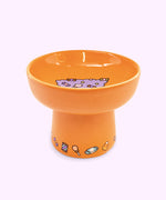 Alternate view of Halloween cat bowl. The bowl features a repeating pattern of candy corn, suckers, chocolates, and more on the base of the pedestal.