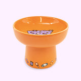 Alternate view of Halloween cat bowl. The bowl features a repeating pattern of candy corn, suckers, chocolates, and more on the base of the pedestal.