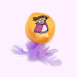 Close-up of the orange ball plush pet toy with purple feathers attached to the bottom. The print on the ball features Vampurr Pusheen and says "spooky cutie."