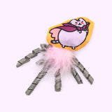 Close-up of the light purple and purple Vampurr plush pet toy with pink feathers and grey ribbons attached to the bottom. 